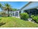 Well-manicured backyard with lush grass, landscaping, and screened in lanai in the distance at 127 Colonial Sw St, Port Charlotte, FL 33952