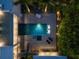 Aerial view of modern home featuring a lit pool, spa, and surrounding tropical landscape at dusk at 1365 Harbor Dr, Sarasota, FL 34239