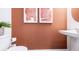 Stylish powder room with pedestal sink, contemporary art and earth tone walls at 15140 Cuzcorro Ct, Nokomis, FL 34275