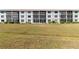 Exterior view of a multi-story building featuring screened lanais, lush landscaping and manicured lawn at 175 Kings Hwy # B5, Punta Gorda, FL 33983