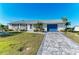 A single-story home with a decorative driveway, manicured lawn, and a vibrant blue garage door at 18082 Eau Gallie S Cir, Port Charlotte, FL 33948