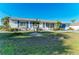 Single-story home featuring blue shutters, a well-maintained lawn, and tropical landscaping at 18082 Eau Gallie S Cir, Port Charlotte, FL 33948