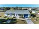 Aerial view of a cozy single-story home with a well-kept lawn, blue shutters, and a long driveway at 18082 Eau Gallie S Cir, Port Charlotte, FL 33948