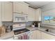 Bright kitchen featuring white cabinets, countertops, and tiled flooring with a window overlooking the exterior at 18082 Eau Gallie S Cir, Port Charlotte, FL 33948
