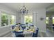 Dining area with a round table, blue chairs, large windows, and a coastal-themed chandelier at 212 Spring Ave, Anna Maria, FL 34216