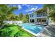 Backyard oasis with a large swimming pool, putting green, lounge chairs, and lush tropical landscaping at 212 Spring Ave, Anna Maria, FL 34216