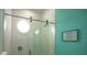 Contemporary glass walk-in shower with round window and textured tile walls and teal accent wall at 212 Spring Ave, Anna Maria, FL 34216