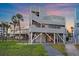 Stunning beach house featuring an elevated design, multiple decks, a spiral staircase, and lush landscaping at 216 Tenacity Ln, Sarasota, FL 34242