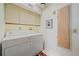 Bright laundry room featuring a washer, dryer, overhead cabinets, and a neutral color scheme at 216 Tenacity Ln, Sarasota, FL 34242