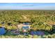 An aerial view captures a community's amenities, including a pool, tennis courts, playground, lake, and clubhouse at 246 Petrel Trl, Bradenton, FL 34212