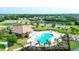Aerial view of a community pool and clubhouse surrounded by lush greenery and several homes and a pond at 246 Petrel Trl, Bradenton, FL 34212