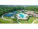 Aerial view showcases a community pool, tennis courts, and clubhouse amidst mature trees and well-maintained landscaping at 246 Petrel Trl, Bradenton, FL 34212