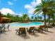 Resort-style community pool with lounge chairs, palm trees, cabanas, and lush landscaping under a sunny sky at 2525 Vaccaro Dr, Sarasota, FL 34231