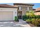 Close-up exterior showcases a tile roof, stone accents, a two-car garage and lush landscaping at 2525 Vaccaro Dr, Sarasota, FL 34231