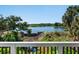 Scenic lake view from the porch, featuring mature trees, rocks, and lush landscaping under a clear blue sky at 2525 Vaccaro Dr, Sarasota, FL 34231