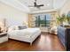 Spacious primary bedroom with tray ceilings, ceiling fan, hardwood floors, and natural lighting at 2525 Vaccaro Dr, Sarasota, FL 34231
