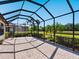 Spacious screened patio with brick flooring overlooking lush backyard and water view at 2525 Vaccaro Dr, Sarasota, FL 34231