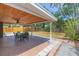 Covered patio with wood ceiling and a ceiling fan overlooks the spacious backyard and lush green landscaping at 301 89Th Ne Ave, St Petersburg, FL 33702