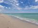 The tranquil turquoise ocean meets the sandy shoreline under a bright, partly cloudy sky at 340 Base E Ave # 314, Venice, FL 34285