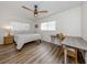 Bright bedroom featuring light wood-look floors, a ceiling fan, and a writing desk near a window at 340 Base E Ave # 314, Venice, FL 34285