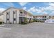 Exterior of a two-story condo building with exterior staircases, parking lot, and manicured landscaping at 340 Base E Ave # 314, Venice, FL 34285