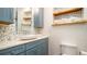 Coastal bathroom featuring blue cabinets, stone countertop, decorative wavy backsplash and open wood shelving at 403 75Th St, Holmes Beach, FL 34217