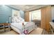 Charming bedroom with blue shiplap walls, a white bed, and rustic barn doors leading to a dressing area at 403 75Th St, Holmes Beach, FL 34217