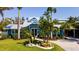 Beautiful blue coastal home featuring lush tropical landscaping, a paver driveway, and a welcoming front entrance at 403 75Th St, Holmes Beach, FL 34217