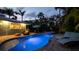 Backyard pool and patio area surrounded by lush tropical landscaping at twilight at 403 75Th St, Holmes Beach, FL 34217