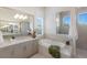 Modern bathroom with soaking tub, dual vanities, tiled shower, and plantation shutters at 508 Blue Shell Loop, Sarasota, FL 34240