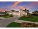 Stunning elevation of this white single-Gathering home with a 3-car garage, lush landscaping, and a brick paver driveway at 508 Blue Shell Loop, Sarasota, FL 34240