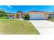 Home exterior featuring a two-car garage, well-manicured lawn and walkway leading to the front door at 5168 Cillette Ave, North Port, FL 34288