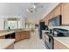 Kitchen featuring oak cabinets, black appliances, tile flooring, and a view into the dining and living areas at 5168 Cillette Ave, North Port, FL 34288