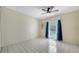 Spacious bedroom with white tile flooring, ceiling fan, and window with blue curtains at 5269 Wedgewood Ln # 36, Sarasota, FL 34235