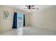 Bedroom with white tile flooring, ceiling fan, and bright window with blue curtains at 5269 Wedgewood Ln # 36, Sarasota, FL 34235