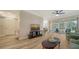 Bright living room with wood floors, a modern TV setup, and sliding glass doors to a screened lanai at 5283 Descanso Ct # 101B18, Sarasota, FL 34238
