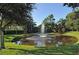 Community pond with fountain feature surrounded by lush landscaping and a blue sky at 5283 Descanso Ct # 101B18, Sarasota, FL 34238