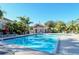 Community pool with a well-manicured deck surrounded by umbrellas, chairs, and tropical landscaping at 5283 Descanso Ct # 101B18, Sarasota, FL 34238