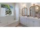 Bright bathroom with double vanities, large windows, and a soaking tub with marble surround at 5782 Sandy Pointe Dr, Sarasota, FL 34233
