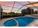 Screened-in pool with attached hot tub and a view of the sunset at 5782 Sandy Pointe Dr, Sarasota, FL 34233