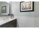 A modern powder room features wainscoting, a gray vanity and a framed art piece at 5978 Anise Dr, Sarasota, FL 34238