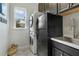 A laundry room features a stacked washer and dryer, black cabinets, sink and window at 5978 Anise Dr, Sarasota, FL 34238