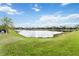 Scenic view of a tranquil pond surrounded by vibrant green grass, trees and beautiful blue skies at 5978 Anise Dr, Sarasota, FL 34238