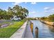 Picturesque waterfront view with a wooden pier, serene water, and a parked car under a large tree in the background at 6415 Midnight Pass Rd # 204, Sarasota, FL 34242