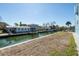 Waterfront backyard with a grassy area, canal access, a dock, and a view of neighboring homes at 654 Jungle Queen Way, Longboat Key, FL 34228