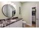 Bathroom featuring a round mirror, marble countertop and a doorway to a walk-in closet at 654 Jungle Queen Way, Longboat Key, FL 34228