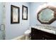 Powder room with a marble countertop and matching mirror and walls, featuring artwork and a glass door shower at 654 Jungle Queen Way, Longboat Key, FL 34228