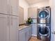 Modern laundry room with gray cabinetry, granite countertop, stainless steel sink and stacked washer and dryer at 654 Jungle Queen Way, Longboat Key, FL 34228