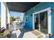 Covered outdoor patio with white wicker seating, a blue painted exterior, and sliding glass doors to the interior at 654 Jungle Queen Way, Longboat Key, FL 34228