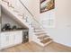 Close up of under-stair bar, staircase with glass railing, and adjacent powder room at 654 Jungle Queen Way, Longboat Key, FL 34228